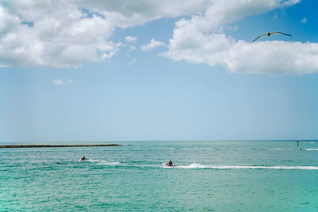 Two waverunners crossing turquoise Gulf water, riders too far away to identify.