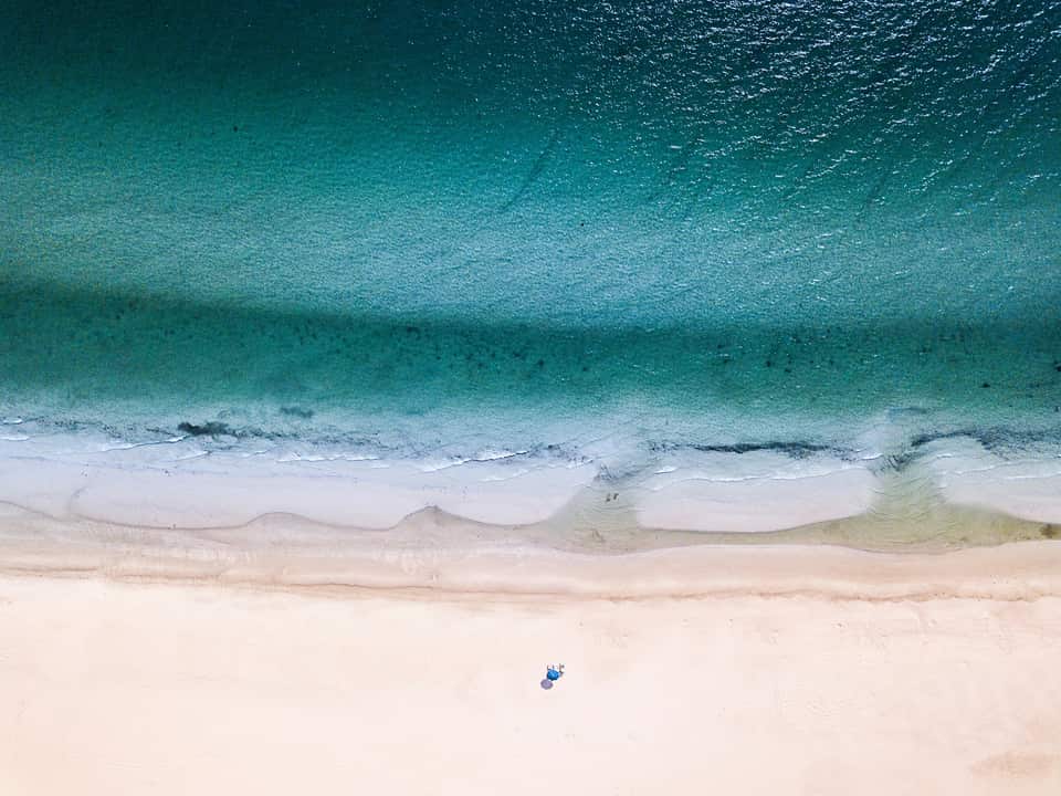 Aerial view straight down at Marco Island's beach, turquoise Gulf water meeting white sand.